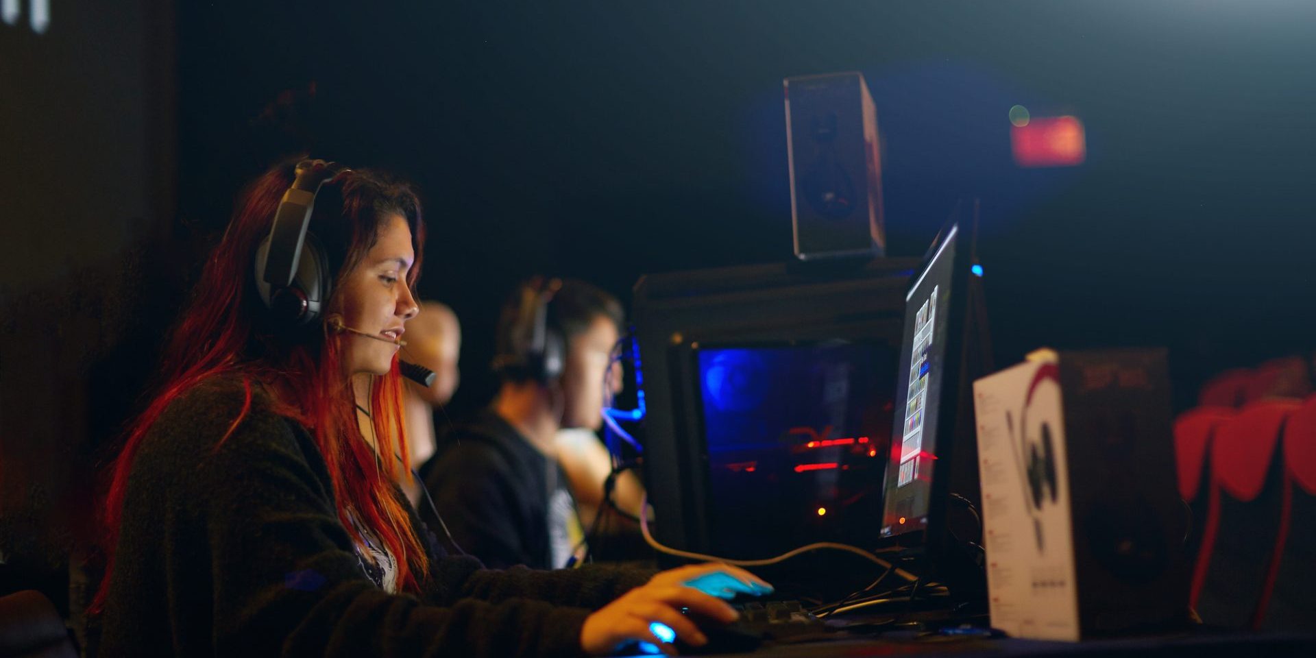 Professional Girl Gamer Plays in MMORPG Strategy Video Game on Her Computer. She's Participating in Online Cyber Games Tournament, Plays at Home, or in Internet Cafe. She Wears Gaming Headset.