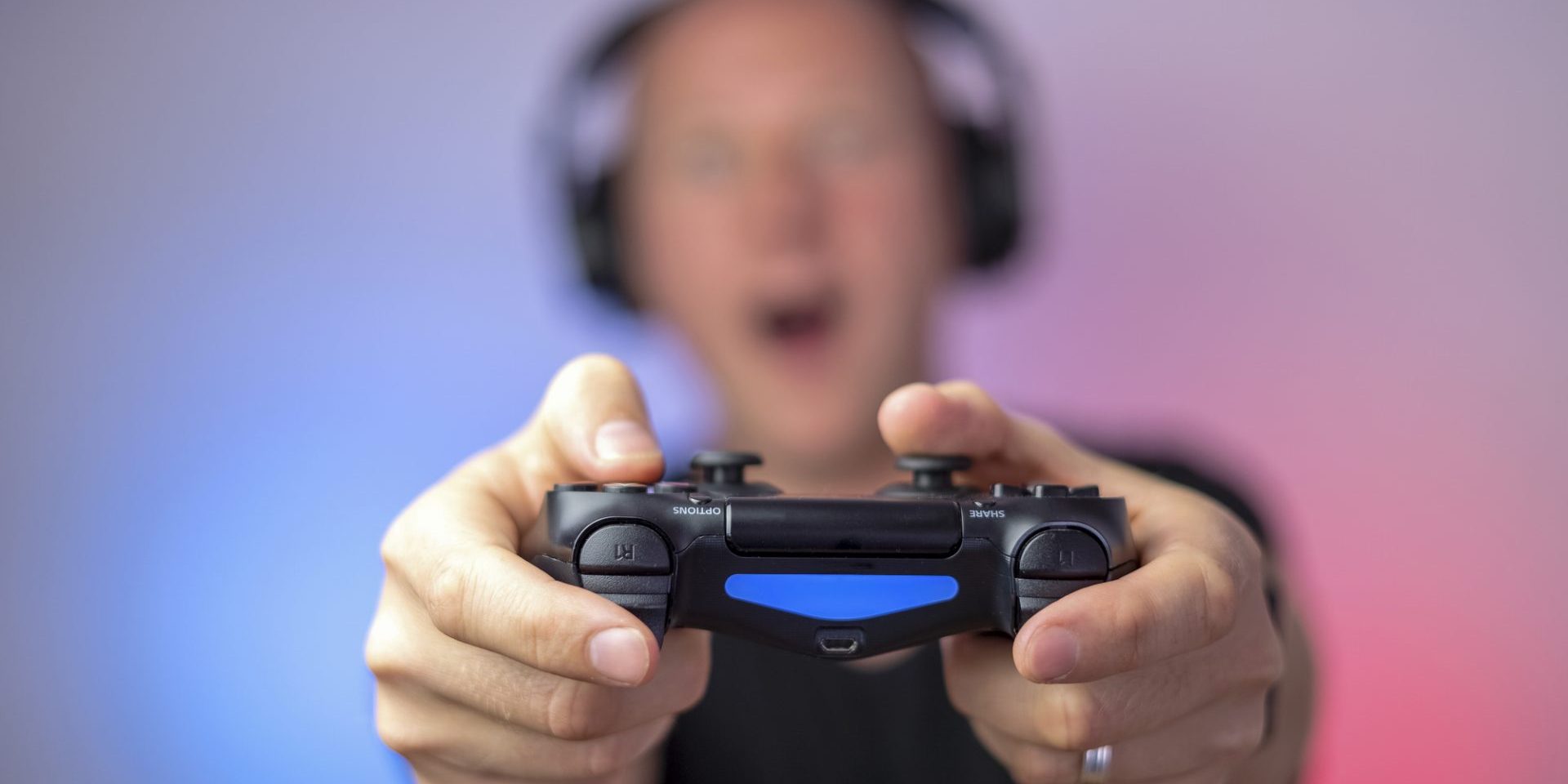 Gamer with headphones and gamepad having a lot of fun. Gamepad in