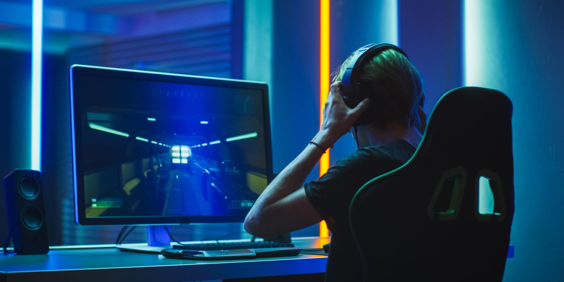 Pro Gamer Plays in the First Person Shooter on His Personal Computer. He Puts on His Headphones. Neon Colored Room. Online eSport Tournament in Action. Shot on Anamorphic Lens.