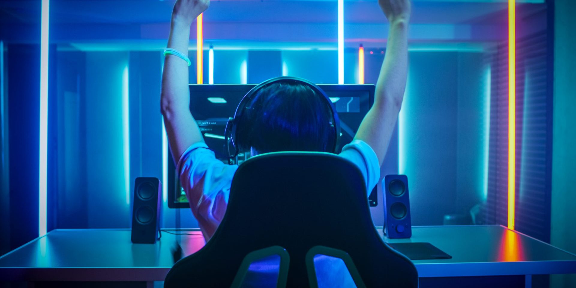 Professional Gamer Playing and Winning in First-Person Shooter Online Video Game on His Personal Computer. Footage Fade out into Bokeh. Room Lit by Neon Lights in Retro Arcade Style. Cyber Sport Championship.