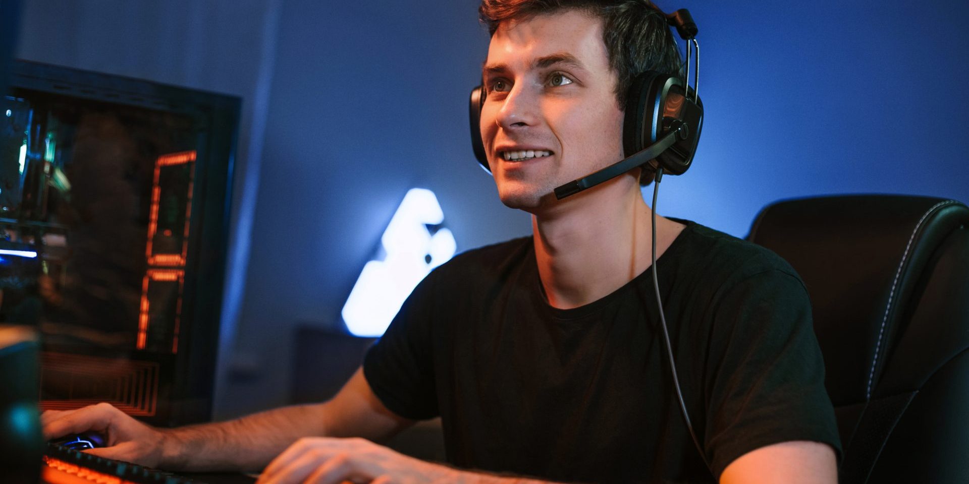 Young Caucasian handsome professional cybersport player training or playing online video game on his PC, participate in team play, preparing for tournaments. Vlogger streaming his game. Cyber sport