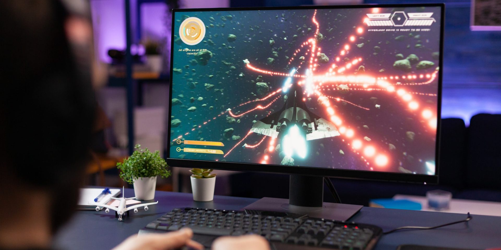 Man playing video games with joystick on computer. Player using controller and wearing headphones to play online game on monitor. Modern person using gaming equipment to have fun.