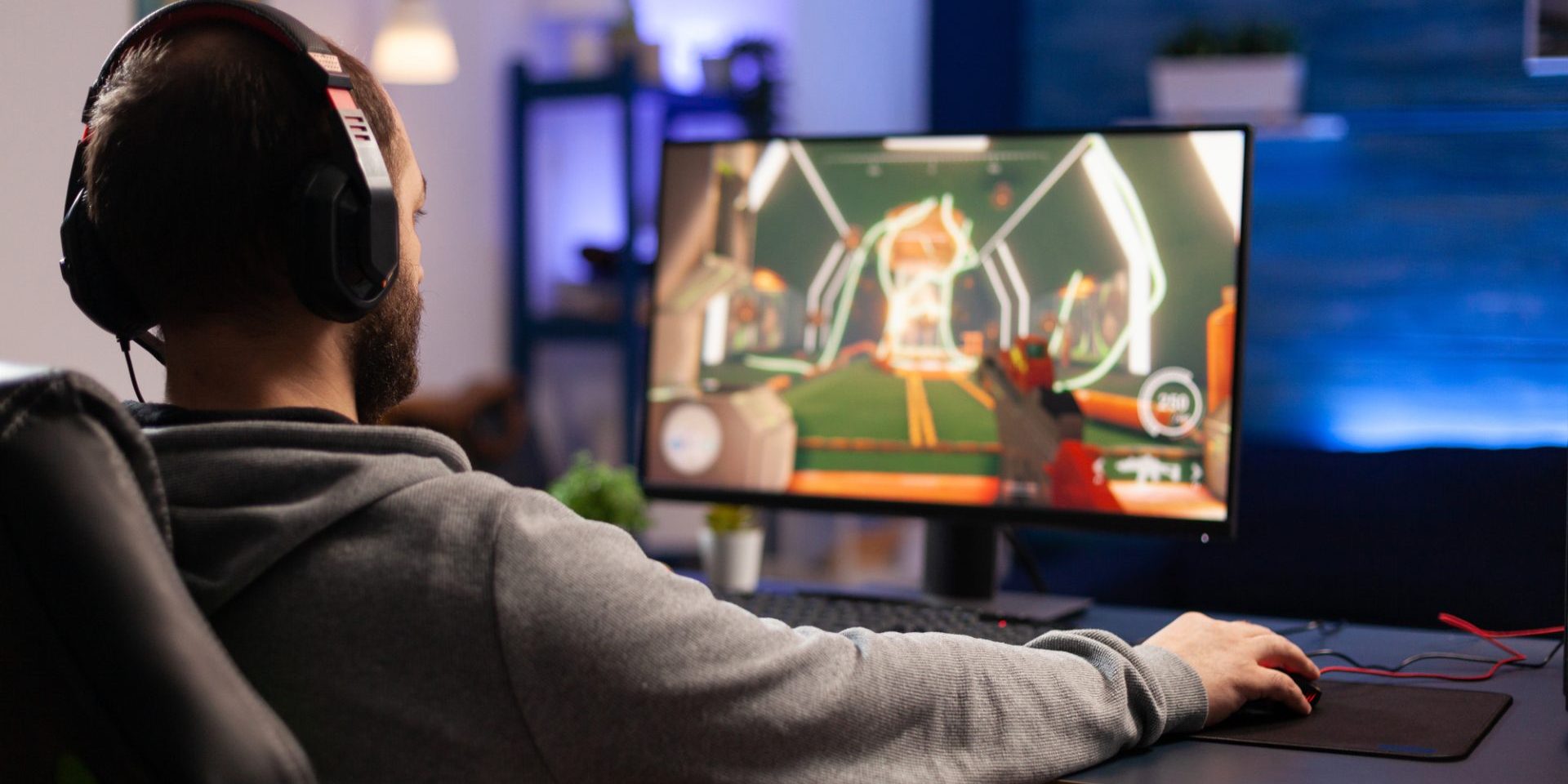 Player using keyboard and mousepad to play video games on computer. Man wearing headphones and playing online game with mouse and gaming equipment. Gamer doing activity for entertainment