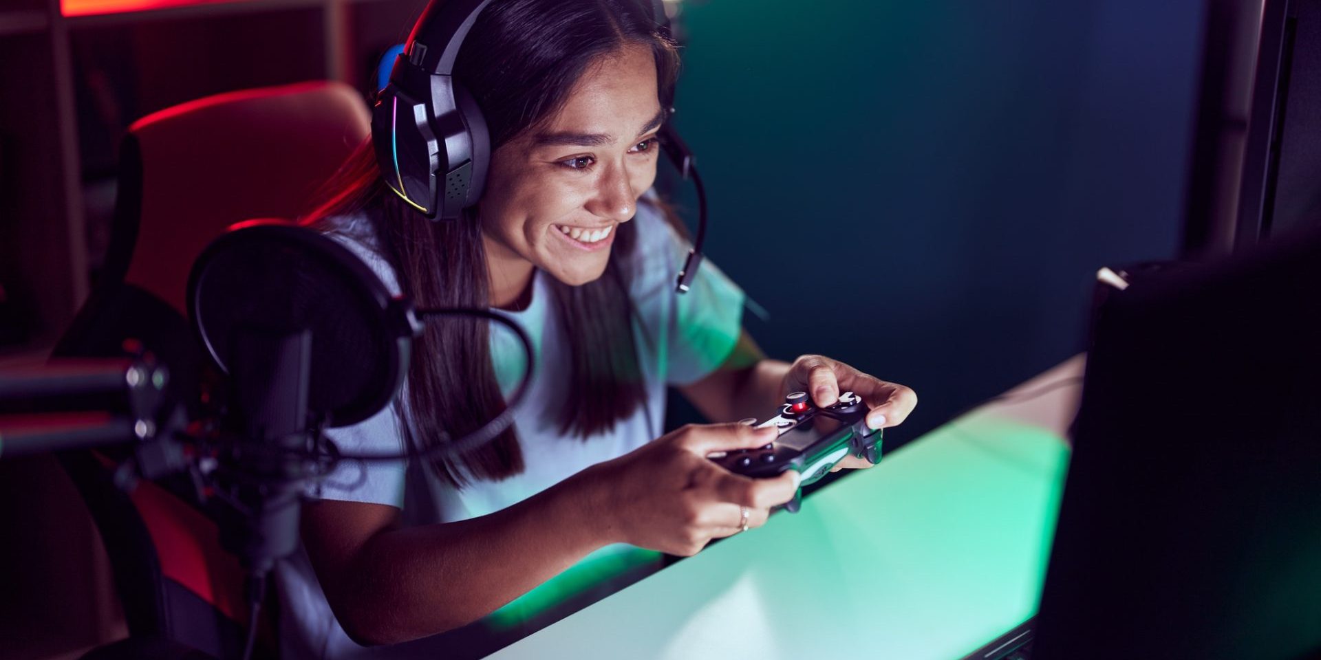 Young beautiful hispanic woman streamer playing video game using joystick at gaming room